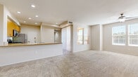 Located in La Quinta, California, this well-designed one-bedroom, one-bathroom residence offers a comfortable and functional single-level layout. The open-concept living and dining area is spacious and filled with natural light from large windows dressed with blinds, and features plush wall-to-wall carpeting and recessed lighting throughout. A sliding glass door leads to an outdoor access point, enhancing the sense of openness. The kitchen is positioned adjacent to the living area and features warm wood-toned cabinetry, a peninsula breakfast bar with a granite-style countertop, stainless steel appliances including a refrigerator and microwave, and easy-care tile flooring. The bedroom is generously sized, with carpet flooring, a ceiling fan, and a bright window overlooking the surroundings. It is complemented by a large walk-in closet outfitted with built-in shelving and hanging rods, offering ample storage. The full bathroom includes a soaking tub and shower combination with clean white surround, a vanity with stone-style countertop, and wood-look flooring. A hallway connects the main living spaces, completing this practical and comfortable floor plan suited for everyday living in the desert resort community of La Quinta.