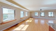 This single-floor urban residence offers an open, airy layout bathed in natural light, with warm bamboo hardwood flooring extending throughout. The expansive living area is a standout feature, lined with multiple large windows framing impressive city skyline views and fitted with a ceiling fan for added comfort. A tray ceiling detail adds architectural interest to the generous open floor plan.

The kitchen is thoughtfully designed with rich, dark wood cabinetry, granite countertops, stainless steel appliances including a range and built-in microwave, and a dedicated wine rack — all centered around a functional layout that flows seamlessly into the living space.

The primary bathroom features a dual-sink vanity with a striking granite countertop, dark wood cabinetry, a large mirror with bar lighting, and bamboo hardwood flooring. A second full bathroom provides a neo-angle glass-enclosed shower, a granite-topped vanity, and coordinating fixtures. A spacious walk-in closet with built-in wire shelving offers ample storage.

Throughout the residence, neutral warm-toned walls, clean white trim, and consistent flooring create a cohesive and inviting aesthetic. The views of the surrounding cityscape, visible from multiple rooms, add a dynamic urban character to this well-appointed space.