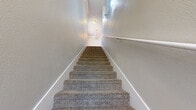 Located in Albuquerque, NM, this well-appointed 3-bedroom, 2-bathroom home offers a practical and comfortable layout across a single floor. The living room makes a strong first impression with crown molding, a ceiling fan, plush carpeting, and elegant French doors that invite natural light and provide outdoor access. An arched interior doorway adds a refined architectural touch. The kitchen is outfitted with dark cabinetry, granite countertops, stainless steel appliances including a refrigerator and microwave, and wood-look flooring that extends throughout the main living areas, creating a cohesive and easy-to-maintain aesthetic. Both bathrooms feature dark wood vanities with granite countertops and wood-look flooring; one includes a shower-tub combo, while the other offers a single-sink vanity. The primary bedroom is generously sized, featuring carpet flooring, a ceiling fan, and a window that lets in natural light, along with access to a spacious walk-in closet with built-in wire shelving on both sides. A dedicated laundry room provides added convenience. Carpeted stairs with a handrail and a delicate chandelier detail connect the levels. Textured walls throughout lend warmth and character to the home's overall ambiance.