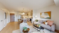 Located at 871 Sibley Memorial Hwy in Lilydale, MN, this thoughtfully designed one-bedroom, three-bathroom residence offers a refined open-concept floor plan with modern finishes throughout. Light hardwood flooring flows seamlessly from the living area into the kitchen, creating a cohesive and airy feel across the main living space.

The chef's kitchen is a standout feature, showcasing crisp white shaker cabinetry, quartz countertops, stainless steel appliances, a wall-mounted range hood, and a wood-paneled center island with bar seating and stylish brass pendant lighting overhead. The space opens naturally into the living room, which is bathed in natural light from large sliding glass doors that lead to a private balcony overlooking lush treetop views.

The bedroom offers a serene retreat with plush carpeting and ample natural light. A dedicated walk-in closet area provides generous storage, and an in-unit stacked washer and dryer adds everyday convenience. Three well-appointed bathrooms serve the residence, including a sleek en-suite featuring a frameless glass walk-in shower with floor-to-ceiling white tile and matte black fixtures. Recessed lighting and a neutral palette throughout lend the space a clean, contemporary ambiance.