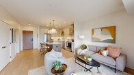 Located at 871 Sibley Memorial Hwy in Lilydale, MN, this thoughtfully designed one-bedroom, three-bathroom residence offers a refined open-concept floor plan with modern finishes throughout. Light hardwood flooring flows seamlessly from the living area into the kitchen, creating a cohesive and airy feel across the main living space.

The chef's kitchen is a standout feature, showcasing crisp white shaker cabinetry, quartz countertops, stainless steel appliances, a wall-mounted range hood, and a wood-paneled center island with bar seating and stylish brass pendant lighting overhead. The space opens naturally into the living room, which is bathed in natural light from large sliding glass doors that lead to a private balcony overlooking lush treetop views.

The bedroom offers a serene retreat with plush carpeting and ample natural light. A dedicated walk-in closet area provides generous storage, and an in-unit stacked washer and dryer adds everyday convenience. Three well-appointed bathrooms serve the residence, including a sleek en-suite featuring a frameless glass walk-in shower with floor-to-ceiling white tile and matte black fixtures. Recessed lighting and a neutral palette throughout lend the space a clean, contemporary ambiance.