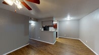 This single-floor residence offers a well-organized and functional layout with consistent wood-look flooring flowing throughout the living areas, kitchen, and bedrooms. The open-concept living area is spacious and bright, featuring a ceiling fan with light fixture, textured ceilings, and a large window fitted with vertical blinds that allows natural light to fill the room. Neutral gray walls provide a clean, modern backdrop throughout the unit.

The kitchen is designed in a galley style and is accessible via a half-wall peninsula that doubles as a breakfast bar with granite countertops. Rich, warm-toned cabinetry lines both walls of the kitchen, complemented by a mosaic tile backsplash, granite countertops, and black appliances including a refrigerator, range, and dishwasher. Recessed lighting above the kitchen ensures ample illumination for meal preparation.

The bedroom is a comfortable, well-proportioned room with its own ceiling fan, darker accent wall, and direct access to a walk-in closet, providing generous storage. The bathroom features a full tub-shower combination with white subway tile surround, maintaining a clean and classic aesthetic. Overall, the space presents a cohesive design with practical finishes and a comfortable, livable ambiance throughout.