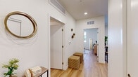 Located at 5256 Federal Blvd in Denver, CO, this well-designed one-bedroom, one-bathroom unit offers a thoughtfully organized layout across a single floor. Light wood-tone flooring runs continuously throughout the space, creating a cohesive and warm aesthetic.

The living room serves as a bright, welcoming focal point, featuring a large sliding glass door that opens onto a private balcony, allowing abundant natural light and outdoor views of the surrounding courtyard. The open-plan design connects the living area seamlessly to the kitchen, which is outfitted with two-tone cabinetry — white upper cabinets and natural wood lower cabinets — paired with white quartz countertops, a kitchen island with an integrated sink, and a full suite of stainless steel appliances including a gas range, microwave, refrigerator, and dishwasher.

The hallway connects the living spaces to the bedroom and bathroom. The bedroom is a comfortably sized retreat with a large window admitting natural light and includes a closet. The bathroom features light wood cabinetry, a white vanity, a full tub-shower combination with marble-style tile surround, and wood-look flooring. Recessed lighting and a clean, neutral palette unify the entire unit.