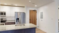 Located in downtown Jacksonville, this single-floor unit at 112 W Adams St artfully combines historic character with contemporary updates. The living area is a standout, featuring original exposed brick walls and large multi-pane windows that frame views of the surrounding urban streetscape while flooding the interior with natural light. Rich hardwood-style flooring flows throughout, complementing the warm tones of the brick.

The kitchen is well-appointed with granite countertops, a navy-accented island with a stainless steel sink, white shaker-style upper cabinetry, dark lower cabinets, a full suite of stainless steel appliances including a French door refrigerator, electric range, and over-the-range microwave, and a classic subway tile backsplash. Recessed lighting keeps the space bright and functional.

The bedrooms feature light wood-style flooring, crisp white walls, and closets with built-in shelving for organized storage. One bedroom retains the building's signature exposed brick corner, adding architectural warmth.

The bathroom is clean and modern, finished with large-format white tile flooring, a tiled tub-shower surround, and brushed nickel fixtures. Throughout the unit, the interplay of historic brick and polished modern finishes creates a distinctive, urban living environment.