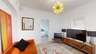 Located at 1663 E Ninth St in Tucson, AZ, this compact yet thoughtfully designed one-bedroom, one-bathroom home offers a cohesive and stylish living experience across a single floor. The living room serves as the heart of the space, immediately drawing attention with its striking gold sputnik chandelier and crisp white walls that amplify natural light from multiple windows fitted with blinds. Light wood-tone flooring runs throughout, lending warmth and visual continuity to every room. A bold, oversized abstract painting adds a vibrant artistic focal point above the plush seating area, complemented by a wood-framed media console and a decorative patterned area rug.

The kitchen is clean and functional, outfitted with white cabinetry featuring matte black hardware, a gas range, ample counter space, and a window above the sink that brings in natural light. The bedroom is a serene retreat, featuring a window that fills the room with daylight, light-toned walls, and a white dresser with matching black hardware. The bathroom maintains the home's consistent white palette, with a white vanity, medicine cabinet mirror, and wood-tone flooring. Every room reflects a deliberate, modern aesthetic that maximizes the utility and comfort of this efficiently sized Tucson home.