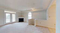Located at 105 Amberley Dr in Blue Bell, Pennsylvania, this single-floor home offers a clean, well-maintained interior with a thoughtful layout and timeless design. The main living area is generously sized, featuring plush wall-to-wall carpeting in a warm neutral tone that complements the soft, light gray walls throughout. A classic fireplace serves as a focal point in the living space, framed by a crisp white mantel with built-in shelving on either side, adding both functionality and visual interest. An elegant arched window allows natural light to pour into the room, enhancing the airy, open atmosphere. A sliding glass door on the adjacent wall provides additional light and access to the exterior. A half-wall partition with a countertop ledge subtly separates the living space from an adjoining area, creating a sense of definition without sacrificing the open-concept feel. Recessed ceiling details add architectural character, while flush-mount lighting ensures the space is well-lit. The overall ambiance is calm and neutral, making it a versatile canvas well-suited for a variety of interior styles. This Blue Bell property combines practical design with comfortable living in a single, cohesive floor plan.