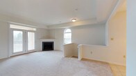 Located at 105 Amberley Dr in Blue Bell, Pennsylvania, this single-floor home offers a clean, well-maintained interior with a thoughtful layout and timeless design. The main living area is generously sized, featuring plush wall-to-wall carpeting in a warm neutral tone that complements the soft, light gray walls throughout. A classic fireplace serves as a focal point in the living space, framed by a crisp white mantel with built-in shelving on either side, adding both functionality and visual interest. An elegant arched window allows natural light to pour into the room, enhancing the airy, open atmosphere. A sliding glass door on the adjacent wall provides additional light and access to the exterior. A half-wall partition with a countertop ledge subtly separates the living space from an adjoining area, creating a sense of definition without sacrificing the open-concept feel. Recessed ceiling details add architectural character, while flush-mount lighting ensures the space is well-lit. The overall ambiance is calm and neutral, making it a versatile canvas well-suited for a variety of interior styles. This Blue Bell property combines practical design with comfortable living in a single, cohesive floor plan.