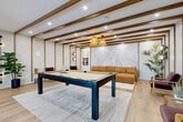 Located at 808 2nd Avenue in Lachine, Québec, these thoughtfully designed common spaces span a single floor and offer a diverse range of amenities for residents and guests. The design language is modern and warm, combining white walls with rich wood beam accents, light hardwood flooring, and carefully curated furnishings throughout.

The centerpiece of the lounge area is a full-size pool table set atop a textured area rug, surrounded by comfortable seating and complemented by woven pendant lights. A botanical-inspired accent wall and large windows allow natural light to fill the room while framing outdoor views. An adjacent full kitchen features a large waterfall-edge island with built-in seating, warm wood cabinetry with under-cabinet lighting, a tile backsplash, and a statement stainless steel hood — ideal for group gatherings.

Dining and lounge seating areas include stylish banquette-style booths with upholstered benches, marble-top tables, and sleek pendant lighting. Two private offices, one enclosed by floor-to-ceiling glass walls with black steel framing, provide functional workspaces. A dedicated meeting room offers a round marble table, cushioned chairs, and a wall-mounted display screen. Two clean, tiled bathrooms complete the floor. Connecting hallways maintain a bright, cohesive aesthetic throughout.