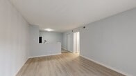 This single-story, 1-bedroom, 2-bathroom residence offers a thoughtfully organized layout across a compact yet efficient floor plan. The open-concept living area features light-toned hardwood-style flooring, soft gray walls, and clean white baseboards, creating a bright and modern aesthetic. A sliding glass door with vertical blinds allows natural light to fill the space while providing outdoor access. The kitchen is defined by a breakfast bar peninsula and is equipped with gray shaker-style cabinetry, marble-look countertops, and a full suite of black appliances, including a refrigerator, electric range, over-the-range microwave, and ample upper and lower cabinet storage. A connecting hallway leads to the private bedroom, which is finished with plush wall-to-wall carpeting, a ceiling fan with light fixture, and two windows that bring in generous natural light. The bedroom benefits from excellent storage, with access to multiple closets — including what appears to be a double-door closet and additional dedicated storage spaces. Two full bathrooms serve the home. Four total closets throughout the unit provide exceptional organizational capacity. The neutral color palette and consistent finishes throughout give the home a cohesive, move-in-ready feel.