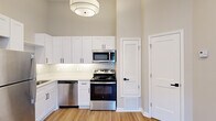Located at 1500 Champions Pines Lane in Augusta, Georgia, this well-appointed one-bedroom, one-bathroom residence offers a thoughtfully designed single-floor layout that maximizes every square foot. The open-concept kitchen and living area serves as the heart of the home, featuring crisp white shaker cabinetry extending to impressive heights, a classic subway tile backsplash, and a full suite of stainless steel appliances including a gas range, built-in microwave, dishwasher, and refrigerator. Light hardwood-style flooring flows throughout the main living areas, complemented by warm neutral wall tones that create a clean, cohesive aesthetic. The living area benefits from abundant natural light through French doors that open to the outdoors, along with recessed lighting overhead. The bedroom is finished with plush carpet and features a vaulted ceiling with a ceiling fan, a natural light-filled window, and a dedicated closet. The bathroom showcases a white vanity with a sleek countertop, matte black fixtures, a round mirror, and elegant lighting. A dedicated closet provides additional storage. This residence offers a practical and modern living experience in a compact, efficient footprint.