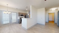 This 2-bedroom, 1-bathroom single-floor unit offers a thoughtfully designed layout with light wood-style flooring and neutral tones throughout, creating a clean and cohesive aesthetic. The open-concept living and kitchen area serves as the heart of the home, where a peninsula-style counter defines the space between the living room and kitchen. The kitchen is fully equipped with stainless steel appliances, including a range, microwave, refrigerator, and dishwasher, complemented by warm wood-toned cabinetry and white countertops. Natural light flows in through shuttered windows and a glass door in the living area. A central hallway connects the bedrooms and bathroom, with panel-style doors and light-colored trim adding to the consistent design language. The primary bedroom features two windows with outdoor views, providing ample natural light, while the second bedroom includes a ceiling fan and its own window. The full bathroom is fitted with a soaking tub and shower combination featuring brushed gold fixtures. A dedicated laundry area with a top-loading washer adds everyday convenience, and a closet provides additional storage. The overall ambiance is bright, modern, and move-in ready.