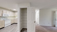 Located in Raleigh, NC, this single-story, 3-bedroom, 2-bathroom home offers a practical and well-organized layout designed for comfortable everyday living. The combined kitchen and living room serves as the heart of the home, with the kitchen featuring white cabinetry, light laminate countertops, wood-look flooring, and a full suite of white appliances including a range, microwave, dishwasher, and refrigerator. A closet with built-in wire shelving provides convenient storage directly off this main living area. The spacious living room is carpeted and filled with natural light from a large window and a glass door that opens to the outdoors, offering views of surrounding greenery. Three carpeted bedrooms provide comfortable retreats, with the generously sized primary bedroom offering ample space and access to a dedicated closet. The secondary bedrooms are well-proportioned, each with windows that bring in natural light. Two bathrooms serve the home, with one featuring a tub-shower combination and wood-look tile flooring. A central hallway connects the bedrooms and bathrooms efficiently. Textured ceilings, clean white walls, and consistent finishes throughout give the home a bright, cohesive aesthetic.