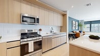 Located at 329 Alfred Ave in Teaneck, NJ, this thoughtfully designed one-bedroom, one-bathroom residence offers a modern open-concept layout across a single floor. Light wood flooring flows throughout, lending warmth and continuity to the space.

The kitchen is a standout feature, equipped with stainless steel appliances including a gas range, built-in microwave, and French door refrigerator. Flat-front light wood cabinetry extends floor to ceiling, complemented by a white tile backsplash and a center island with bar seating — ideal for casual dining or meal prep.

The living area is anchored by a striking deep blue accent wall, providing a bold yet sophisticated contrast to the otherwise neutral palette. Large windows invite natural light and offer views of surrounding greenery, creating a bright and airy atmosphere.

The bedroom is a comfortable and well-appointed retreat, featuring windows with outdoor views, light-toned walls, and easy access to a dedicated closet. The full bathroom includes tile flooring, a wood-finished vanity with a white countertop, a large mirror, and a shower-tub combination with dark tile surround.

Recessed lighting throughout and clean architectural lines give the entire residence a polished, contemporary feel well-suited to modern living.