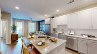 This thoughtfully designed one-bedroom, one-bathroom residence offers a cohesive open-concept floor plan that maximizes every square foot. The kitchen serves as a central hub, showcasing granite countertops, white and gray shaker cabinetry, stainless steel appliances, and a large island with bar seating — ideal for both cooking and casual dining. Hardwood-style flooring flows seamlessly throughout the space, adding warmth and continuity.

The living room is a standout, anchored by a bold teal shiplap accent wall adorned with decorative art panels. Large windows and a glass door invite generous natural light and provide outdoor access, while a ceiling fan adds comfort. The open sightlines between the kitchen and living area create an inviting, connected atmosphere.

The bedroom features a textured shiplap accent wall, a ceiling fan, and a large window that fills the room with natural light. It connects directly to a walk-in closet with wire shelving systems offering ample storage, as well as a private bathroom. The bathroom is finished with granite countertops, gray cabinetry, a framed vanity mirror, and a glass-enclosed walk-in shower, all set on hardwood-style flooring for a clean, modern aesthetic.