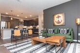 This single-floor residence showcases a cohesive contemporary design with thoughtful finishes carried throughout each space. The kitchen serves as a central highlight, featuring flat-front dark cabinetry extending to the ceiling, light quartz countertops, subway tile backsplighting, stainless steel appliances, and a generous island with bar seating. Recessed lighting and pendant fixtures illuminate the space, while light wood-look flooring flows seamlessly underfoot.

The living area offers a welcoming, open layout with the same warm wood-look flooring, neutral walls, and ample room for comfortable furnishings. Multiple bedrooms provide restful retreats, each carpeted for comfort. The primary bedroom features a bold navy accent wall, ceiling fan, and natural light from a window with draping curtains. Additional bedrooms maintain a calm, neutral palette with soft carpet and practical storage space.

Two full bathrooms mirror each other in style, each appointed with dark vanity cabinetry, light quartz countertops, wood-look flooring, and a tiled tub-shower combination with subway tile surround. The overall ambiance throughout is modern and refined, with a consistent palette of dark cabinetry, neutral tones, and clean architectural lines.