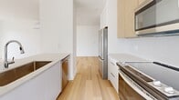 This thoughtfully designed two-bedroom, two-bathroom unit in East Hants, Nova Scotia, offers a clean, modern aesthetic across a single well-organized floor. Light hardwood flooring runs throughout the living spaces, complementing the crisp white walls and creating a bright, cohesive feel.

The open kitchen is outfitted with white cabinetry, light wood upper cabinets, quartz countertops, and stainless steel appliances including a refrigerator, electric range, dishwasher, and built-in microwave. A window above the counter frames views of mature pine trees, filling the space with natural light. The kitchen flows directly into a generous living area featuring large windows and a sliding glass door that invite abundant sunlight and overlook lush greenery.

The primary bedroom is a comfortable retreat with its own ensuite bathroom, a walk-in closet with built-in shelving, and a wall-mounted mini-split heating and cooling unit. The ensuite features a glass-enclosed shower, a wood-toned vanity, and large-format tile flooring. The second bedroom is bright and airy, with a oversized window offering peaceful treed views and baseboard heating.

A second full bathroom mirrors the refined design of the ensuite, complete with a soaker tub, modern wood vanity, and large tile floors. A clean hallway connects all rooms, reinforcing the unit's efficient and contemporary layout.