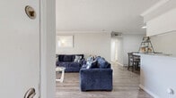 This single-floor residence offers a practical and comfortable layout featuring 2 bedrooms, 3 bathrooms, and four closets. The open-concept living area is anchored by wood-look flooring, crown molding, and a textured ceiling, creating a clean and cohesive aesthetic. The spacious living room flows seamlessly into the combined dining and kitchen area, which is separated by a half-wall pass-through. The kitchen features white cabinetry, speckled laminate countertops, a stainless steel sink, and black appliances, including a full-size refrigerator and dishwasher, all set along a galley-style layout that maximizes efficiency. The primary bedroom is a well-sized retreat with carpet flooring, a ceiling fan, and access to a walk-in closet outfitted with built-in shelving and dual hanging rods. The second bedroom also features carpet flooring, a ceiling fan, and a window that brings in natural light. Each of the three bathrooms is finished with wood-look tile flooring, speckled vanity countertops, and tub-shower combinations. A hallway connects the private areas of the home, providing a clear and organized flow throughout the space. With four closets total, storage is a notable strength of this well-structured residence.