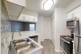 This single-floor residence in Dearborn, Michigan offers a practical and comfortable layout with 2 bedrooms, 2 bathrooms, and ample storage across five closets. The living room is a welcoming space featuring wood-look flooring, neutral gray walls, a textured ceiling, and a classic fireplace as a focal point. Natural light filters in through windows dressed with horizontal blinds, and a door provides access to an outdoor area. The kitchen is well-equipped with white shaker-style cabinetry, light countertops, a double stainless steel sink, a tile backsplash, and stainless steel appliances including a range, microwave, dishwasher, and refrigerator. Both bedrooms are finished with wood-look flooring and neutral tones; the primary bedroom includes a ceiling fan and a window with outdoor views, while the second bedroom also features closet access. Each bathroom is finished with light wood-look flooring, white cabinetry, and a tiled tub-shower combination. A hallway connects the rooms efficiently, and the entrance provides a welcoming transition into the home. Throughout, consistent flooring and a cohesive neutral color palette create a clean, move-in-ready aesthetic.