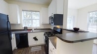This three-story, 3-bedroom, 2.5-bathroom home offers a thoughtfully organized layout across multiple levels, providing distinct spaces for living, sleeping, and entertaining. The kitchen is a functional and attractive centerpiece, featuring crisp white cabinetry that extends to the ceiling for ample storage, dark granite-style countertops, and black appliances including a gas range, built-in microwave, and dishwasher. A double-basin sink is positioned beneath a window that invites natural light and views of the surrounding greenery, creating a pleasant workspace. The warm hardwood-style flooring adds continuity and character to the space. With 3 bedrooms and 2.5 bathrooms distributed across three floors, this home provides excellent separation between common areas and private retreats, making it well-suited for a variety of living arrangements. The multi-floor design offers generous vertical space and opportunities for varied room functions, from gathering areas to quiet personal spaces. The overall ambiance is clean, practical, and welcoming, with a neutral color palette that provides a versatile backdrop for any style of furnishing or décor.