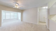 This single-story unit in Macon, Georgia, offers a thoughtfully arranged layout with a neutral color palette and a mix of flooring materials throughout. The living area is generously sized, featuring plush carpeting, a ceiling fan with light fixture, and multiple windows fitted with blinds that allow natural light to filter in. An adjacent dining area is distinguished by warm hardwood-style flooring and an elegant chandelier overhead, creating a welcoming space for everyday use.

The galley-style kitchen is efficiently designed with white cabinetry, white countertops, a stainless steel double sink, and white appliances including a range and refrigerator. Hardwood-style flooring continues through this area, complementing the bright, clean aesthetic. A pass-through connects the kitchen to the main living spaces.

The bedrooms are carpeted and comfortably sized, each equipped with ceiling fans and windows that bring in natural light. Closet space is available, and the layout accommodates a variety of furniture arrangements. A hallway connects the bedrooms to the bathroom, which features warm hardwood-style flooring, white cabinetry with ample counter space, a large mirror with vanity lighting, and a tiled tub-shower combination. Throughout the unit, clean white trim and neutral walls contribute to a bright, cohesive ambiance.