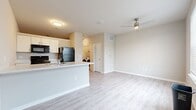 Located at 1300 N Lancaster Rd in South Elgin, IL, this efficient 540-square-foot, single-floor apartment offers a well-designed open-concept layout. The combined kitchen and living area serves as the heart of the unit, featuring light wood-look vinyl plank flooring that runs throughout the entire space, creating a clean and cohesive aesthetic. The kitchen is equipped with white cabinetry, light quartz-style countertops, a stainless steel sink, and black appliances including a refrigerator, electric range, built-in microwave, and dishwasher. The living area is bright and airy, benefiting from natural light streaming through double windows fitted with white horizontal blinds, and is complemented by a ceiling fan overhead. The bathroom includes a full-size soaking tub and shower combo with built-in shelving, a toilet, and a vanity, all finished with the same wood-look flooring. A dedicated walk-in closet provides ample storage with multi-tiered wire shelving systems. The unit also includes an in-unit washer, as visible in the dollhouse overview. Neutral warm-toned walls throughout contribute to a clean, modern, and move-in-ready atmosphere.