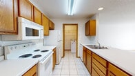 Located at 1810 39th St S in Fargo, North Dakota, this single-floor, 2-bedroom, 1-bathroom unit offers a functional and comfortable layout. The galley-style kitchen is well-appointed with warm oak cabinetry, white appliances including a range, refrigerator, built-in microwave, and dishwasher, complemented by light tile flooring and a double-basin sink. A dedicated laundry area is accessible directly from the kitchen, adding everyday convenience. The living room is bright and inviting, featuring plush carpeting, a ceiling fan, baseboard heating, and a sliding glass door that opens to an outdoor patio and brings in natural light. Both bedrooms are carpeted with neutral tones, warm wood trim, and recessed lighting. The primary bedroom offers a generous footprint, while the second bedroom benefits from a window with outdoor views and baseboard heating. The full bathroom includes a tub-shower combination and clean, simple finishes. Throughout the unit, warm oak wood trim provides a cohesive, classic aesthetic. The overall layout is practical and efficient, making good use of the available space across every room.
