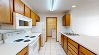 Located at 1810 39th St S in Fargo, North Dakota, this single-floor, 2-bedroom, 1-bathroom unit offers a functional and comfortable layout. The galley-style kitchen is well-appointed with warm oak cabinetry, white appliances including a range, refrigerator, built-in microwave, and dishwasher, complemented by light tile flooring and a double-basin sink. A dedicated laundry area is accessible directly from the kitchen, adding everyday convenience. The living room is bright and inviting, featuring plush carpeting, a ceiling fan, baseboard heating, and a sliding glass door that opens to an outdoor patio and brings in natural light. Both bedrooms are carpeted with neutral tones, warm wood trim, and recessed lighting. The primary bedroom offers a generous footprint, while the second bedroom benefits from a window with outdoor views and baseboard heating. The full bathroom includes a tub-shower combination and clean, simple finishes. Throughout the unit, warm oak wood trim provides a cohesive, classic aesthetic. The overall layout is practical and efficient, making good use of the available space across every room.