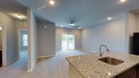 Located at 7408 Lorenzo Ln in Louisville, Kentucky, this single-story home offers a thoughtfully designed layout with a cohesive, modern aesthetic throughout. The open-concept living and dining area is anchored by plush carpeting, recessed lighting, and a ceiling fan, creating a comfortable and functional space. A sliding glass door leads directly to an outdoor deck, filling the room with natural light and providing easy access to the exterior. The kitchen is a standout feature, showcasing rich dark wood cabinetry, granite-style countertops, and a full suite of black appliances including a refrigerator, electric range with over-the-range microwave, and a deep sink with a modern faucet. Wood-look flooring adds warmth and durability to the kitchen, while a dedicated pantry provides ample storage. The bedrooms are generously sized, finished with soft carpeting, ceiling fans, and windows that allow for natural light. The bathroom is well-appointed with a granite-topped vanity with dark cabinetry, a tub-shower combination, and wood-look tile flooring. Neutral gray tones carried throughout the home create a clean, move-in-ready atmosphere with a contemporary feel.