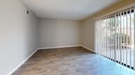 Located at 933 Peach Ave in El Cajon, California, this one-bedroom, two-bathroom single-floor residence offers a practical and well-appointed layout. Wood-look plank flooring runs throughout the unit, providing a cohesive and easy-to-maintain finish across all rooms.

The combined kitchen and living room area forms the heart of the home. The living space features a sliding glass door fitted with vertical blinds, allowing natural light to filter in while offering access to the outdoors. A decorative lattice partition adds subtle architectural character near the entryway. The kitchen is efficiently arranged with white cabinetry, a full-size refrigerator, an electric range, and a window above the sink that brings in additional natural light.

The bedroom is a comfortable, well-sized retreat featuring a ceiling fan with light fixture, a window with vertical blinds, and the same wood-look flooring found throughout. Both bathrooms are clean and functional, each equipped with a vanity, mirror, and a bathtub/shower combination. The textured ceilings are consistent throughout the unit, and neutral warm-beige wall tones create a calm, move-in-ready atmosphere. A hallway connects the private areas of the residence, contributing to a clear and organized floor plan.