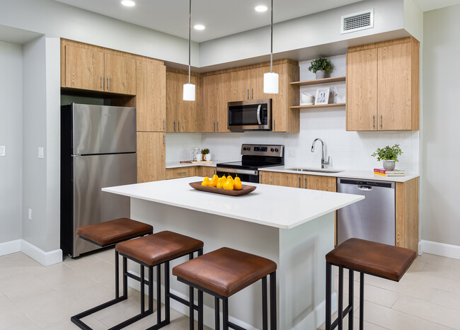 Cocina de concepto abierto con encimeras de cuarzo, isla, electrodomésticos de acero inoxidable y placa para salpicaduras de azulejos - Avalon Doral