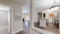 This thoughtfully designed single-floor residence offers two bedrooms and two bathrooms within a comfortable and functional layout. The living room serves as the heart of the home, featuring a tile-surround fireplace, ceiling fan, and a glazed door that invites natural light while providing outdoor access. Dark hardwood-style flooring flows throughout the main living areas, adding warmth and visual continuity.

The kitchen is equipped with stainless steel appliances, including a refrigerator, microwave, and range, set against rich dark cabinetry. A granite-topped breakfast bar opens the kitchen to the adjacent dining area, which is accented by a pendant light fixture. A closet off the kitchen provides additional storage.

Both bathrooms feature granite vanity countertops, dark wood cabinetry, framed mirrors, and brushed nickel hardware, reflecting a consistent design aesthetic throughout. A dedicated in-unit laundry space accommodates a full-size washer and dryer.

The bedrooms are carpeted for comfort and include ample closet space with bi-fold doors. The primary bedroom offers a spacious layout with a connected bathroom and walk-in closet access via a hallway. Neutral tones and textured ceilings are present throughout, creating a clean and cohesive living environment.