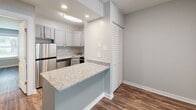 Located at 1511 Starling Dr in Henrico, Virginia, this single-floor home offers a clean, modern aesthetic with thoughtful updates throughout. Rich hardwood-style flooring flows seamlessly across the living areas, complementing the neutral gray walls and bright white trim that create a cohesive, contemporary feel.

The living room is bright and welcoming, with a large front-facing window dressed with vertical blinds that invite abundant natural light. The updated kitchen is well-appointed with granite countertops, gray shaker-style cabinetry, stainless steel appliances including a range, microwave, refrigerator, and dishwasher, and recessed lighting overhead. A peninsula counter with additional granite workspace extends into the adjacent area, ideal for casual dining or meal prep.

The bedrooms are spacious and comfortable, each featuring ceiling fans with light fixtures and hardwood-style flooring. One bedroom includes a generous closet and a conveniently tucked-in in-unit washer and dryer, adding everyday practicality. Another bedroom benefits from a bright window with views of the surrounding greenery.

The bathroom features a full tub and shower combination with built-in shelving, clean white surrounds, and brushed nickel fixtures. The overall ambiance of the home is fresh, functional, and move-in ready.