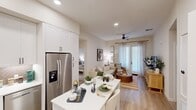 Located at 501 Avenida Vaquero in San Clemente, CA, this two-bedroom, two-bathroom residence offers a thoughtfully designed single-floor layout with a bright, coastal-inspired aesthetic throughout. The open-concept kitchen and living area serves as the heart of the home, featuring white shaker cabinetry, a herringbone tile backsplash, stainless steel appliances including a French door refrigerator and gas range, and a white kitchen island that doubles as a dining space. Light wood-style flooring flows through the main living area, which is anchored by a ceiling fan and a glass patio door that invites natural light and outdoor access. The primary bedroom offers plush carpet, a ceiling fan, and a large window, while its en-suite bathroom impresses with a dual-sink vanity with white countertops, a walk-in glass shower, a soaking tub, and direct access to a dedicated closet with built-in shelving. The second bedroom is equally well-appointed with soft carpet, a ceiling fan, and ample natural light. A second full bathroom mirrors the refined finishes found throughout the home. A stacked in-unit washer and dryer adds everyday convenience. Neutral tones and recessed lighting lend a clean, modern ambiance to every room.