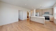 Located at 1997 S Acoma St in Denver, CO, this single-story residence offers a clean, modern aesthetic throughout its open and well-designed layout. Light wood-tone flooring runs continuously across the living areas and bedrooms, complementing the crisp white walls and recessed lighting that give the space a bright, airy feel.

The open-concept kitchen and living area serves as the central hub of the unit. The kitchen features light wood cabinetry, a stainless steel refrigerator with an in-door water and ice dispenser, and a peninsula with a white quartz countertop — ideal for casual dining or food preparation. The adjoining living and dining area is generously proportioned, with multiple windows fitted with horizontal blinds that allow for controlled natural light.

The bedrooms are well-sized, each with light wood flooring, neutral walls, and windows offering outdoor views of the surrounding Denver neighborhood. One bedroom includes sliding glass door access to a private balcony.

Two bathrooms showcase upscale finishes throughout. The primary bathroom features large-format marble-style tile flooring, a dual-sink floating vanity with brushed gold fixtures, a wide mirror with bar lighting, and a soaking tub with matching tile surround. The secondary bathroom includes a glass-enclosed walk-in shower with the same marble-style tile, a floating vanity, and access to a walk-in closet.