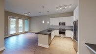 Located at 850 Arbor Way in Blue Bell, Pennsylvania, this single-floor residence offers a well-designed, contemporary living environment with a cohesive neutral palette and quality finishes throughout. The open-concept kitchen serves as a central highlight, featuring a large island with a dark countertop and undermount sink, crisp white cabinetry extending to the ceiling, a classic tile backsplash, stainless steel appliances including a gas range and built-in microwave, and elegant pendant lighting accented by track lighting overhead. The kitchen flows seamlessly into a generous living area finished with warm hardwood flooring and abundant natural light from large windows and a glass door leading to the outdoors. The bedrooms offer plush wall-to-wall carpeting, neutral wall tones, and windows with blinds that allow for natural light and privacy. The bathroom is appointed with a tiled tub-shower combo fitted with a sliding glass door, a grey vanity with a white solid-surface countertop, an undermount sink with chrome fixtures, and a large mirror with overhead lighting and marble-look tile flooring. Clean white baseboards and trim throughout provide a polished, finished look, while the thoughtful layout and modern design elements create a comfortable and functional living space.