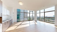 Located at 1282 Boylston Street in Boston's vibrant Fenway neighborhood, this generously proportioned one-bedroom, two-bathroom residence offers a sophisticated modern living experience. The open-concept living, dining, and kitchen area is a true highlight, wrapped in dramatic floor-to-ceiling glass curtain walls that flood the space with natural light and frame sweeping panoramic views of the Boston skyline and surrounding cityscape. Light-toned hardwood flooring runs throughout the main living areas, complementing the clean white walls and contemporary aesthetic. The kitchen features a streamlined design with two-tone cabinetry combining warm wood and gloss white finishes, stainless steel appliances including a refrigerator, oven, and built-in microwave, all set against the backdrop of expansive city views. The spacious bedroom is carpeted and served by well-organized closets, including a walk-in closet with built-in shelving. Both bathrooms are finished with large-format marble-look tile, a soaking tub with shower, a wall-mounted wood vanity, and polished chrome fixtures. A dedicated utility room and multiple additional storage spaces round out this thoughtfully designed residence, offering both style and functionality in one of Boston's most sought-after locations.
