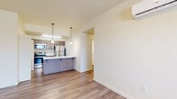 This thoughtfully designed 2-bedroom, 2-bathroom residence offers a functional and modern single-floor layout. The open-concept kitchen and living area serves as the heart of the home, featuring a peninsula with a white quartz countertop, double stainless steel sink, and stylish pendant lighting. The kitchen is equipped with stainless steel appliances, including a refrigerator, range, and microwave, complemented by warm wood-toned cabinetry. Light wood-style flooring flows throughout the main living areas, enhancing the bright and airy ambiance. The living room opens to a private balcony through a glass door, allowing natural light to fill the space. A wall-mounted mini-split system provides efficient climate control. The primary bedroom is a comfortable retreat, offering generous proportions and plush carpeting. Both bathrooms are clean and functional, with one featuring a full soaking tub and shower combination with brushed nickel fixtures. A dedicated in-unit laundry room houses a full-size side-by-side washer and dryer. Additional storage is provided by a hallway closet. The layout is completed by a well-proportioned hallway connecting all rooms for easy navigation throughout the residence.