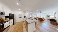 Located at 3625 Frankford Ave in Panama City, FL, this single-floor, 3-bedroom, 2-bathroom home offers a thoughtfully designed open-concept layout. Light wood-tone flooring runs throughout, unifying the living, kitchen, and dining areas in a bright, cohesive aesthetic. The kitchen is well-appointed with white shaker cabinetry, granite countertops, a subway tile backsplash, stainless steel appliances including a refrigerator, range, and microwave, plus a central island with a built-in sink and pendant lighting overhead. The open layout flows seamlessly into the living room, which features a ceiling fan, large windows allowing generous natural light, and views of surrounding greenery. The primary bedroom is a comfortable retreat with warm lighting and a dedicated closet featuring built-in wire shelving. Two full bathrooms carry consistent finishes with granite-topped white vanities, large mirrors, and tub-shower combinations. A clean, well-lit hallway connects the private bedrooms and bathrooms. Two closets provide practical storage throughout. The overall ambiance is modern and airy, with a neutral white palette and natural wood tones creating a welcoming, move-in-ready atmosphere suited for everyday living.