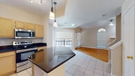 This two-floor residence offers a well-designed layout with a cohesive blend of finishes throughout. The open-concept main living area connects the kitchen and living room seamlessly, with light tile flooring in the kitchen transitioning to warm hardwood in the living space. The living room is a standout area, featuring crown molding, arched windows that invite abundant natural light, and a tile-surround fireplace as a central focal point.

The kitchen is equipped with stainless steel appliances, including a refrigerator, electric range, and built-in microwave. Light maple cabinetry is paired with dark granite countertops, and a central island provides additional workspace. Pendant lighting and track lighting illuminate the area effectively.

The bedrooms are carpeted and finished with crown molding and ceiling fans, offering a comfortable and quiet retreat. The bathrooms mirror the kitchen's design language, featuring light maple cabinetry, dark granite countertops, tile flooring, and large mirrors. The primary bathroom includes an extended vanity with angled cabinetry and a separate water closet. A secondary bathroom provides a tub-shower combination with similar finishes throughout.