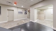 Located at 406 S Boulder Ave in downtown Tulsa, Oklahoma, this fitness facility offers a thoughtfully designed workout environment across a single floor. The space is divided into two distinct functional zones, each tailored to a specific type of training.

The cardio zone features a row of stationary cycling bikes arranged along a long, corridor-style room, flanked by large-scale black-and-white sports photography and wall-mounted flat-screen televisions. Polished concrete flooring runs throughout this area, complementing the clean, neutral-toned walls and a suspended drop-tile ceiling with recessed lighting.

The strength training area transitions to durable rubber flooring and houses a full rack of hex dumbbells, adjustable weight benches, kettlebells, and a cable machine — providing a comprehensive free-weights and resistance training setup. Additional wall-mounted TVs and motivational artwork, including a bold "No Excuses" framed print, reinforce the athletic atmosphere.

A connecting corridor greets visitors upon entry with an inspirational oversized canvas print, setting an energetic tone for the space. The entry and open areas feature polished concrete floors, recessed lighting, and mirrored walls that enhance the sense of openness. The overall design is modern, clean, and purposeful — creating an environment well-suited for focused, high-performance training.