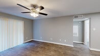 This thoughtfully designed 1-bedroom, 1-bathroom residence offers a practical and comfortable single-floor layout. The open living area is finished with rich wood-look flooring and neutral gray walls, creating a clean and versatile backdrop for any décor. A ceiling fan with integrated lighting serves as a functional centerpiece overhead, and vertical blinds on the sliding door allow for adjustable natural light. The galley-style kitchen is efficiently organized with dark cabinetry, white countertops, and black appliances including a refrigerator, microwave, and electric range, all set above light-toned flooring for a modern contrast. The generously sized primary bedroom features plush wall-to-wall carpeting, a ceiling fan, and a window with vertical blinds that invite natural light. A dedicated closet provides ample storage within the bedroom. The bathroom is clean and bright, featuring a full tub-shower combination with white subway tile surround and brushed nickel fixtures. A hallway connects the rooms, completing the efficient floor plan. Throughout the space, consistent neutral tones, white trim, and ceiling fans contribute to a cohesive, move-in-ready ambiance.