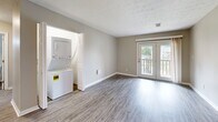 Located at 2845 Palumbo Dr in Lexington, Kentucky, this well-appointed one-bedroom, one-bathroom unit offers a thoughtfully designed single-floor layout. The open-concept living and kitchen area is finished with light-toned luxury vinyl plank flooring, neutral gray walls, and clean white trim, creating a bright and cohesive aesthetic throughout.

The kitchen features white shaker-style cabinetry, dark granite countertops, and black appliances including a range, microwave, dishwasher, and refrigerator. A pass-through window connects the kitchen to the living area, enhancing the sense of openness. The living room offers ample space for everyday living and includes access to a private balcony overlooking a landscaped communal courtyard complete with a fire pit, seating area, and grilling station.

A dedicated laundry closet houses a stacked washer and dryer unit, adding significant convenience. The bedroom is carpeted for comfort, features a ceiling fan with light, a window with outdoor views, and a double-door closet providing generous storage. The bathroom is equipped with a white vanity, dark granite countertop, and a large mirror with overhead lighting. This unit combines practical functionality with clean, modern finishes throughout.