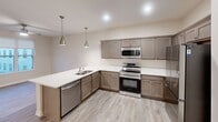 Located at 900 Third St SE in Cedar Rapids, Iowa, this thoughtfully designed one-bedroom, one-bathroom residence offers a comfortable and functional single-floor layout. Light-toned luxury vinyl plank flooring flows throughout the main living areas, lending a clean, cohesive aesthetic.

The kitchen is a standout feature, outfitted with gray shaker-style cabinetry, crisp white countertops, and a full suite of stainless steel appliances including a refrigerator, range, microwave, and dishwasher. Recessed lighting and pendant fixtures illuminate the space, while an L-shaped layout maximizes storage and prep area.

The bedroom is finished with plush carpeting and features a ceiling fan, a closet with built-in shelving, and a large window overlooking the surrounding Cedar Rapids cityscape, allowing for ample natural light.

The bathroom is clean and modern, appointed with a wood-toned vanity, white countertop, a full tub-shower combination, and light wood-look flooring. A notable convenience is the in-unit stacked washer and dryer, neatly tucked within the bathroom space.

The overall ambiance is bright, neutral, and move-in ready, with a contemporary design that balances practicality and style in a compact, efficiently organized floor plan.