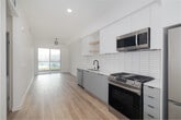 Located at 1450 Cloverfield Blvd in Santa Monica, California, this modern single-floor residence showcases a clean, contemporary design with an emphasis on bright, open living. Light wood-tone flooring runs consistently throughout, complementing the crisp white walls and creating a cohesive, airy aesthetic.

The open-concept kitchen and living area serves as the heart of the unit. The kitchen is outfitted with white flat-panel cabinetry, open shelving, a subway tile backsplash, light quartz countertops, and stainless steel appliances including a gas range, microwave, refrigerator, and dishwasher. A matte black faucet adds a refined contrast. The living area flows seamlessly from the kitchen toward a full-width sliding glass door that invites natural light and provides outdoor access, with a ceiling fan overhead.

The bedroom is generously proportioned, featuring a tray ceiling detail, a sunlit window, and direct access to the hallway leading to the bathroom. The bathroom is appointed with distinctive large-format hexagonal floor tile in warm gray, a modern floating vanity with matte black fixtures, a round mirror with a sleek black frame, and a tiled tub-shower combination. The entry area includes a keypad-equipped front door and a built-in utility panel, completing this well-designed Santa Monica residence.