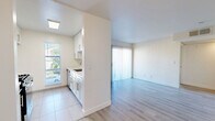 Located at 1250 N June St in the heart of Los Angeles, CA, this 2-bedroom, 2-bathroom unit offers a thoughtfully designed single-floor layout with a bright, clean aesthetic. Light wood-style laminate flooring runs throughout the living areas and bedrooms, complementing the crisp white walls and creating a cohesive, modern feel.

The living room serves as the central gathering space, highlighted by a tiled fireplace and a sliding glass door fitted with vertical blinds that opens to a private balcony with views of surrounding greenery. Natural light flows generously into the space, enhancing the airy ambiance.

Both bedrooms are well-proportioned, featuring the same wood-style flooring and neutral tones. The primary bedroom includes a mirrored sliding closet, while the second bedroom offers easy access to the main hallway. A dedicated closet provides additional storage.

The two bathrooms maintain a consistent clean design, each featuring a tub-shower combination with tile surround, a white vanity with undermount sink and chrome fixtures, and large mirrors to amplify light. Tile flooring in the bathrooms contrasts subtly with the rest of the unit.

The kitchen, visible in the floor plan, features white cabinetry and connects efficiently to the living area, supporting an open, functional flow throughout the home.