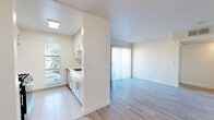 Located at 1250 N June St in the heart of Los Angeles, CA, this 2-bedroom, 2-bathroom unit offers a thoughtfully designed single-floor layout with a bright, clean aesthetic. Light wood-style laminate flooring runs throughout the living areas and bedrooms, complementing the crisp white walls and creating a cohesive, modern feel.

The living room serves as the central gathering space, highlighted by a tiled fireplace and a sliding glass door fitted with vertical blinds that opens to a private balcony with views of surrounding greenery. Natural light flows generously into the space, enhancing the airy ambiance.

Both bedrooms are well-proportioned, featuring the same wood-style flooring and neutral tones. The primary bedroom includes a mirrored sliding closet, while the second bedroom offers easy access to the main hallway. A dedicated closet provides additional storage.

The two bathrooms maintain a consistent clean design, each featuring a tub-shower combination with tile surround, a white vanity with undermount sink and chrome fixtures, and large mirrors to amplify light. Tile flooring in the bathrooms contrasts subtly with the rest of the unit.

The kitchen, visible in the floor plan, features white cabinetry and connects efficiently to the living area, supporting an open, functional flow throughout the home.
