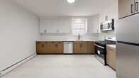 Located at 130 New Road in Parsippany-Troy Hills, NJ, this two-story, one-bedroom, one-bathroom residence offers a well-organized layout across its two levels. The main floor hosts the majority of the living space, including a spacious living room bathed in natural light from large windows that frame views of surrounding greenery. Rich, dark hardwood floors flow throughout the living areas and bedroom, lending warmth and continuity to the space.

The kitchen has been thoughtfully renovated with a clean, modern aesthetic, featuring two-tone cabinetry — white upper cabinets paired with warm wood-toned lower cabinets — set against a white subway tile backsplash. Stainless steel appliances, including a gas range, dishwasher, and microwave, complement the light tile flooring.

The bedroom is a comfortable, well-proportioned room featuring hardwood floors, natural light from a window, and two closet doors offering generous storage. The unit also includes six closets in total, providing exceptional storage throughout.

The renovated bathroom features large-format white tile flooring, a glass-enclosed walk-in shower with marble-style tile surround, matte black fixtures, and a wood-toned vanity. A dedicated laundry area adds everyday convenience. A classic staircase with wood treads and white risers connects the two floors, completing this well-appointed residence.