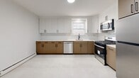 Located at 130 New Road in Parsippany-Troy Hills, NJ, this two-story, one-bedroom, one-bathroom residence offers a well-organized layout across its two levels. The main floor hosts the majority of the living space, including a spacious living room bathed in natural light from large windows that frame views of surrounding greenery. Rich, dark hardwood floors flow throughout the living areas and bedroom, lending warmth and continuity to the space.

The kitchen has been thoughtfully renovated with a clean, modern aesthetic, featuring two-tone cabinetry — white upper cabinets paired with warm wood-toned lower cabinets — set against a white subway tile backsplash. Stainless steel appliances, including a gas range, dishwasher, and microwave, complement the light tile flooring.

The bedroom is a comfortable, well-proportioned room featuring hardwood floors, natural light from a window, and two closet doors offering generous storage. The unit also includes six closets in total, providing exceptional storage throughout.

The renovated bathroom features large-format white tile flooring, a glass-enclosed walk-in shower with marble-style tile surround, matte black fixtures, and a wood-toned vanity. A dedicated laundry area adds everyday convenience. A classic staircase with wood treads and white risers connects the two floors, completing this well-appointed residence.