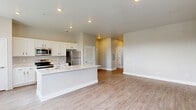 Located at 1105 Blain Ave in Indianapolis, Indiana, this two-story home offers a thoughtfully designed layout across two evenly proportioned floors. The main level centers around an open-concept kitchen and living area, where light wood-tone flooring, recessed lighting, and an abundance of windows create a bright and airy atmosphere. The kitchen is equipped with white shaker-style cabinetry, stainless steel appliances including a range, microwave, and refrigerator, and a white quartz island with a built-in sink — ideal for both cooking and casual entertaining. A half bathroom on the main floor adds everyday convenience. The upper level houses both bedrooms, including a generously sized primary bedroom with its own dedicated closet featuring wire shelving. The second bedroom is carpeted and filled with natural light from multiple windows overlooking lush greenery. Three closets total provide ample storage throughout the home. The three bathrooms include a clean, tiled tub-shower combination and wood-look flooring. Neutral warm-gray walls throughout maintain a cohesive, modern aesthetic. A dedicated laundry area and a hallway connecting the upper-floor rooms round out the functional layout of this move-in-ready Indianapolis home.