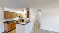 Located at 5959 North 78th Street in Scottsdale, Arizona, this single-floor, 2-bedroom, 2-bathroom residence offers a practical and well-organized layout. Wood-look flooring runs consistently throughout the home, complementing the neutral white walls and textured ceilings found in most rooms.

The galley-style kitchen is efficiently designed with warm wood cabinetry lining both walls, dark countertops, a double-basin sink, and black appliances including a range and refrigerator. A peninsula with matching countertop extends into the adjacent dining area, creating a natural transition between the two spaces. A hallway off the kitchen connects the living areas to the rest of the home.

The living room is bright and open, featuring French doors that invite natural light and provide outdoor access. A secondary bedroom also benefits from natural light through a window with blinds. The primary bedroom is a comfortable size and connects to a hallway with built-in wood cabinetry for additional storage.

Both bathrooms are functional in design, each featuring wood vanities with dark countertops, large mirrors, and tub-shower combinations with clean white surrounds. The overall layout is straightforward and efficient, making effective use of the available space throughout the home.